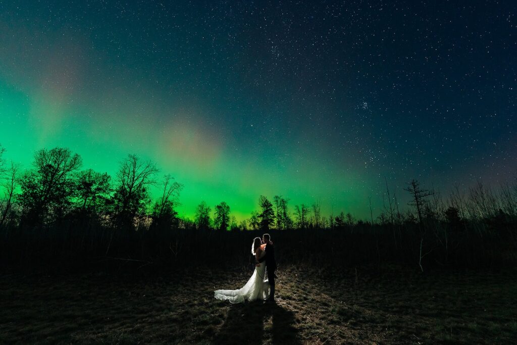 Wedding-style couple portrait beneath aurora borealis in Minnesota