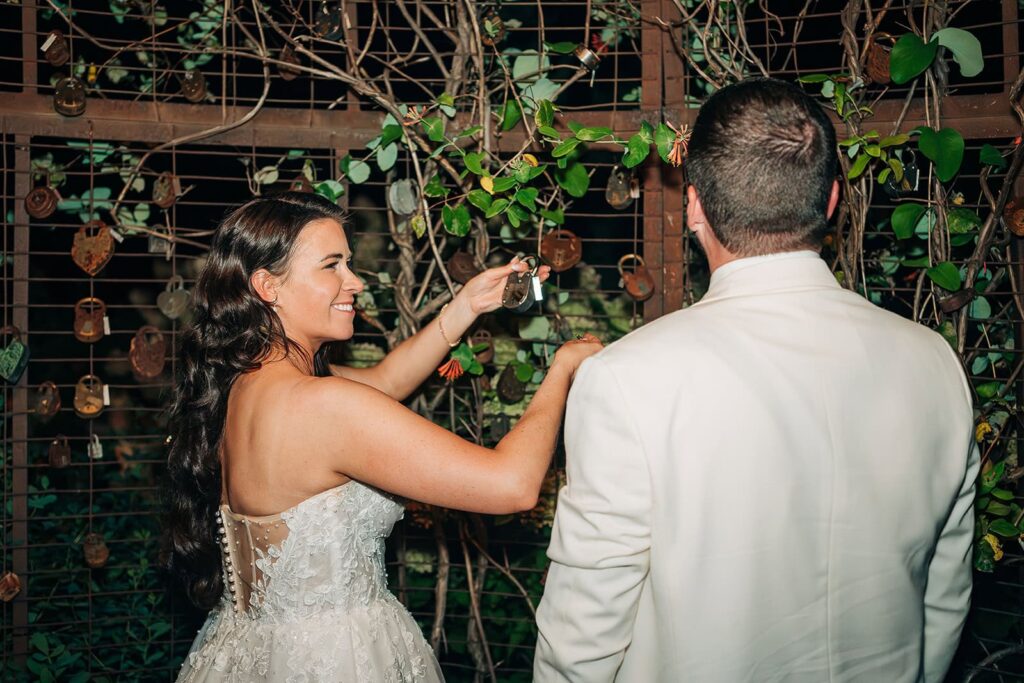 bride and groom adding their padlock to the locks of love gate