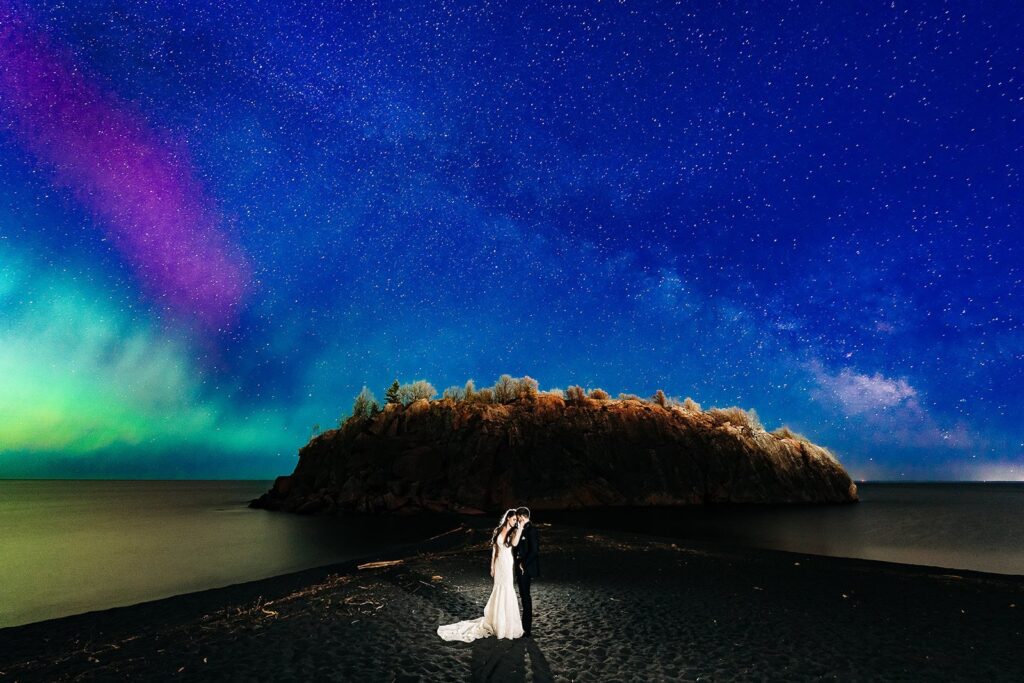 Northern Lights illuminating a couple on Minnesota’s North Shore during a night portrait