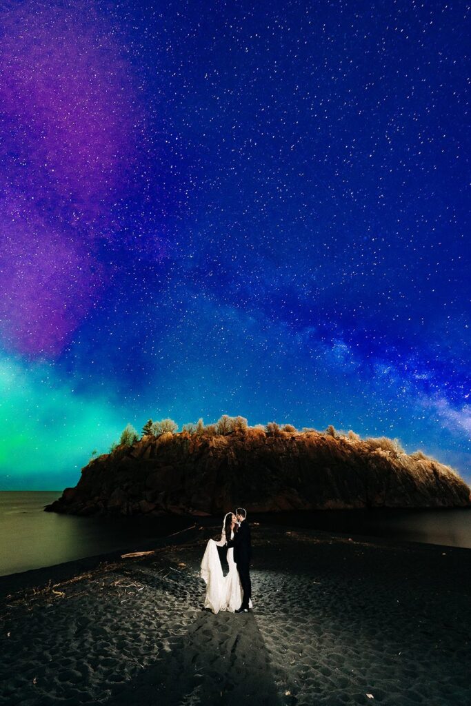 Couple embracing under colorful Northern Lights on Minnesota’s North Shore at night