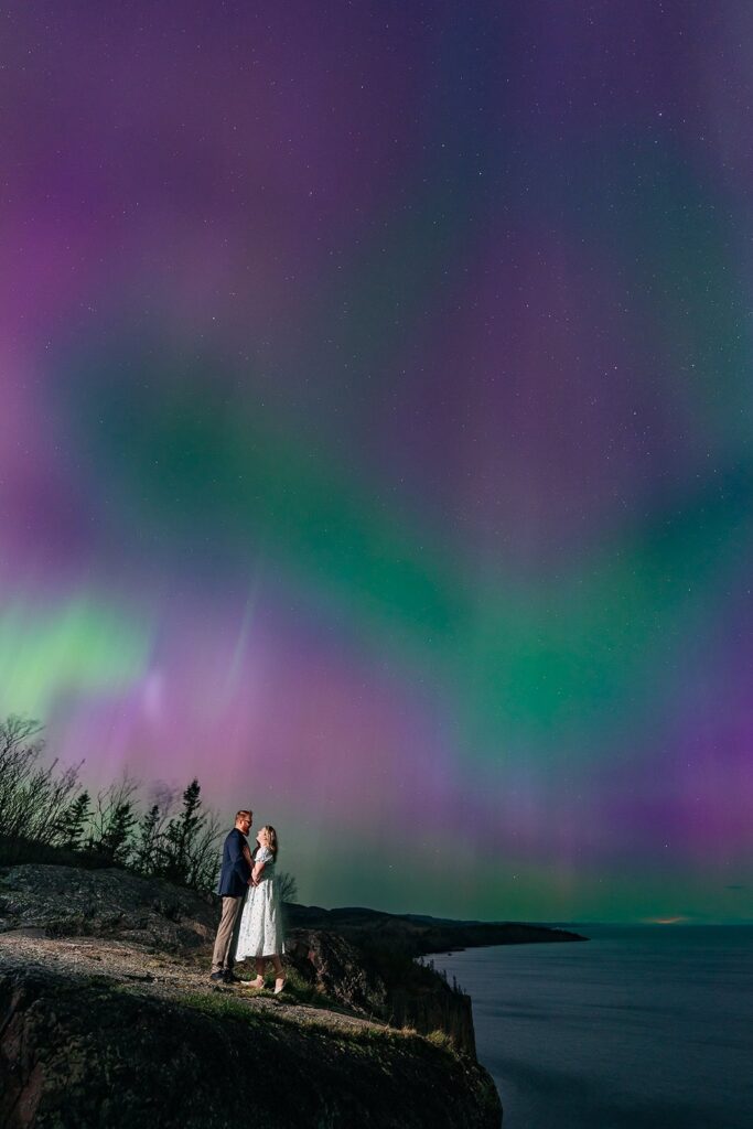 Aurora borealis glowing above a couple on the Lake Superior shoreline, North Shore MN