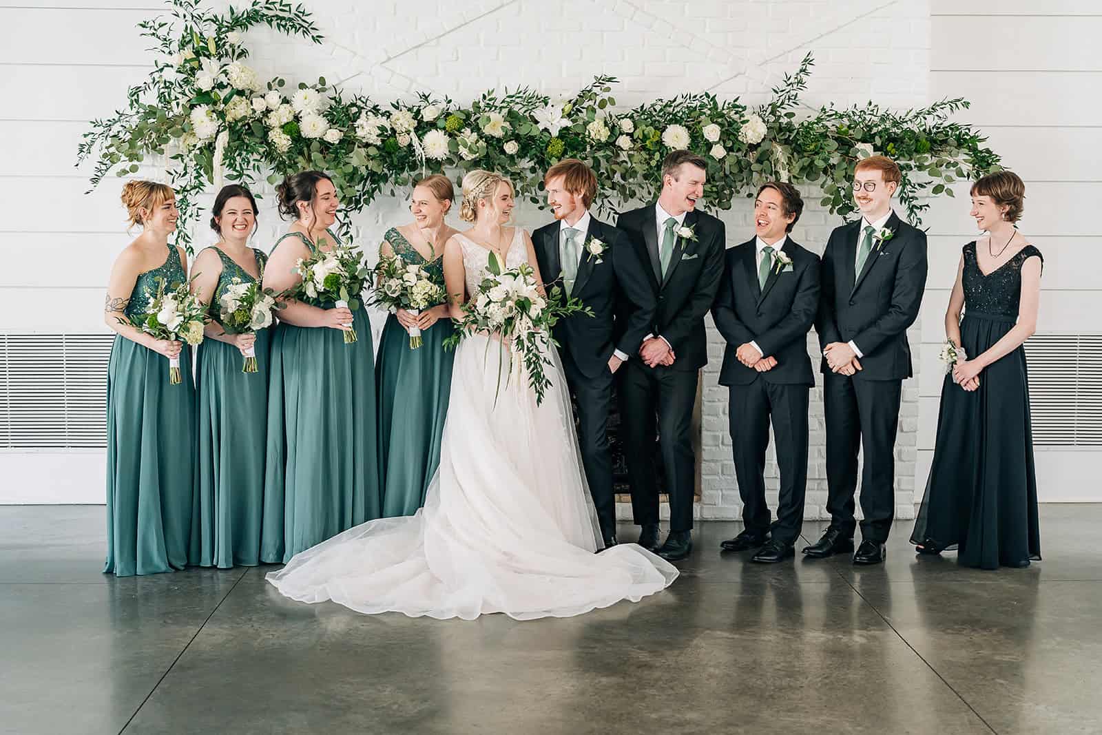 Bride and groom laughing during indoor wedding party portraits